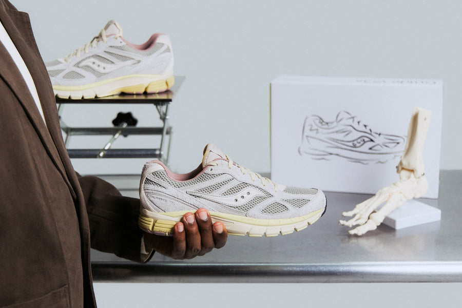 A handheld grey sneaker in front of a metal table.