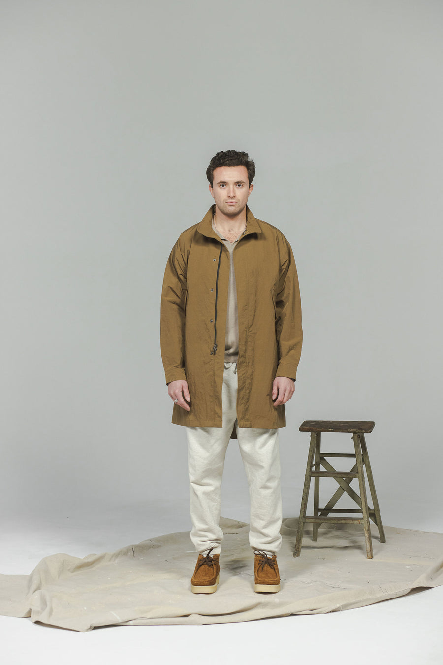 A man in a long brown coat and sweatpants.