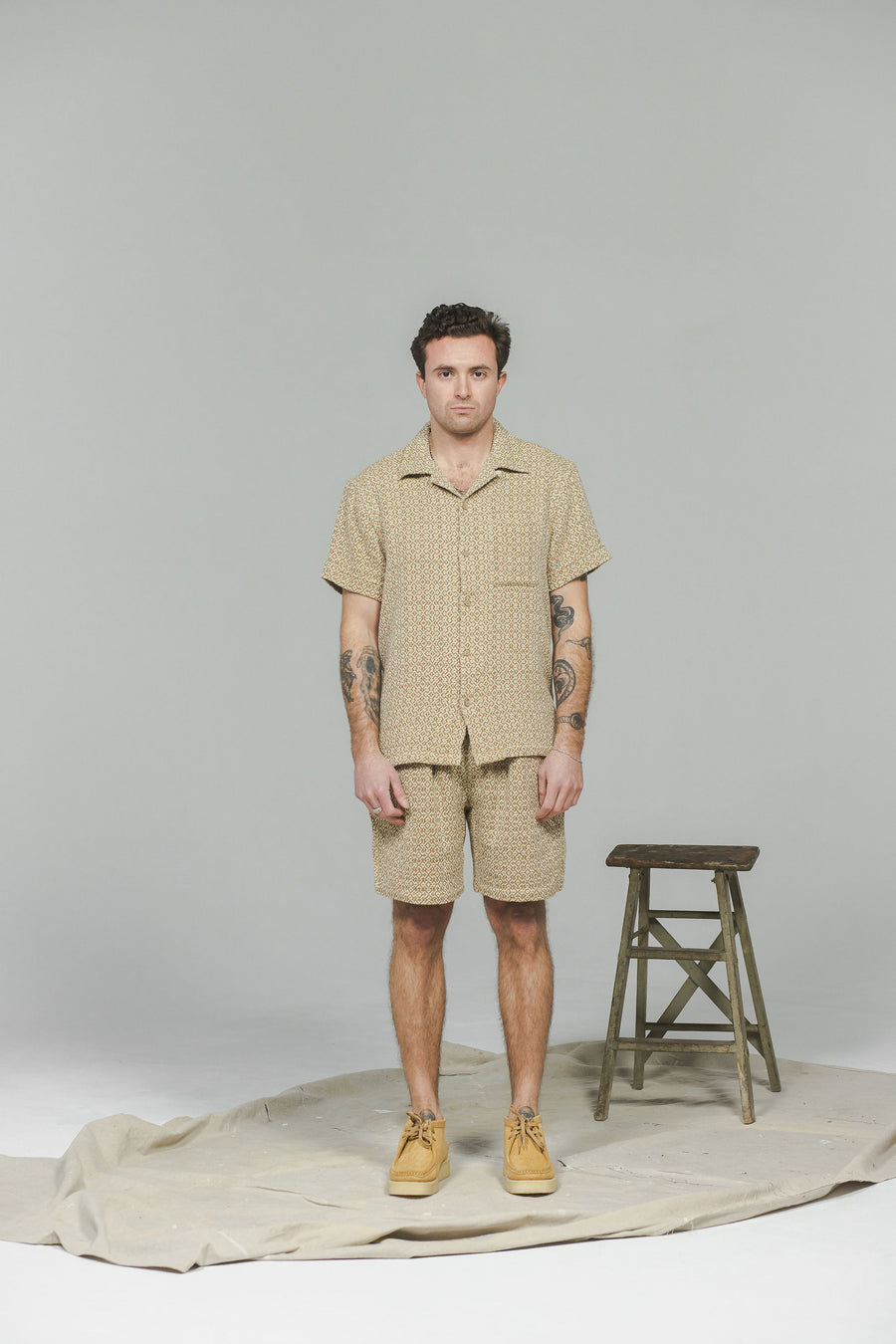 A man in a tan short sleeve shirt and matching shorts.