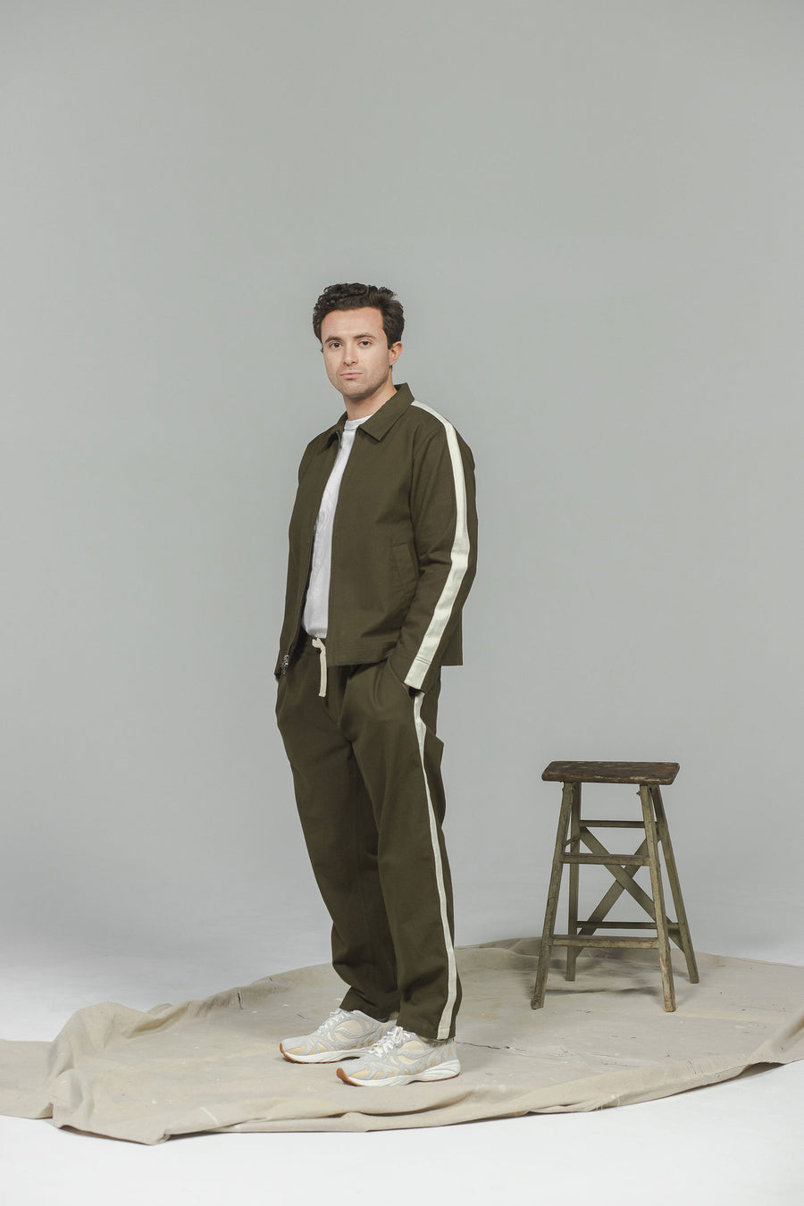 A man in an olive tracksuit and white sneakers.