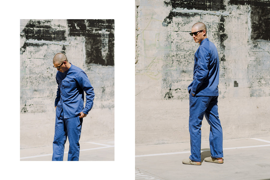 A diptych of a man in a french blue worksuit against a concrete wall.