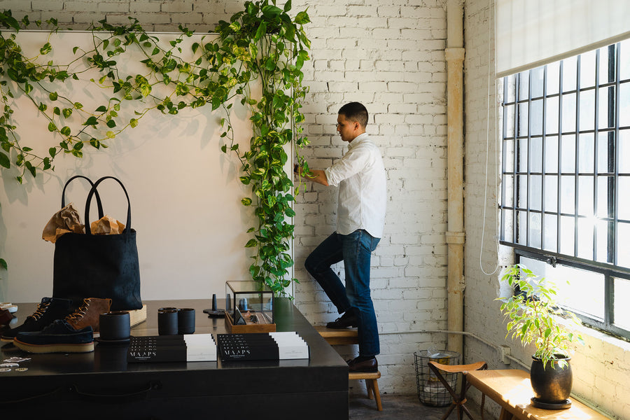 A man restocks jeans while standing on a stepstool.