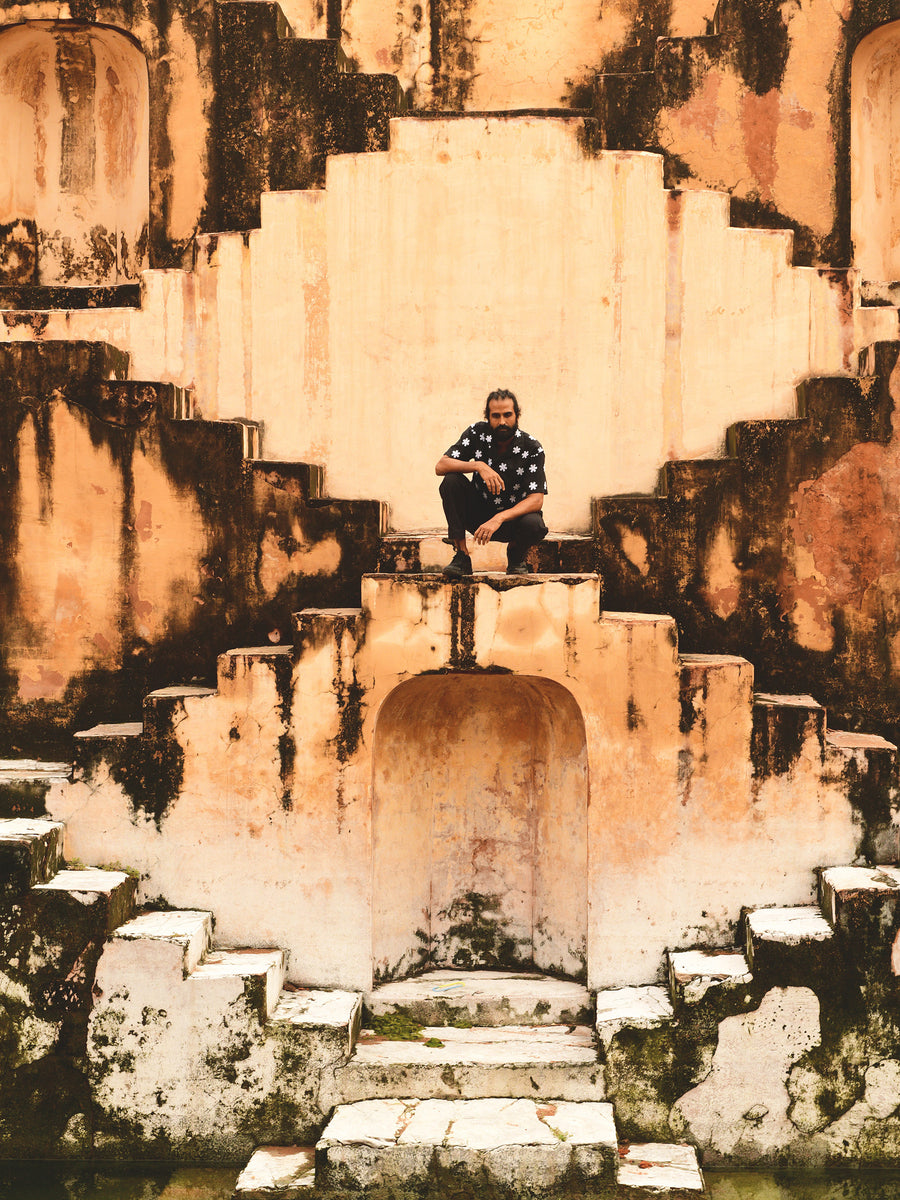 A man crouches in a staircase.