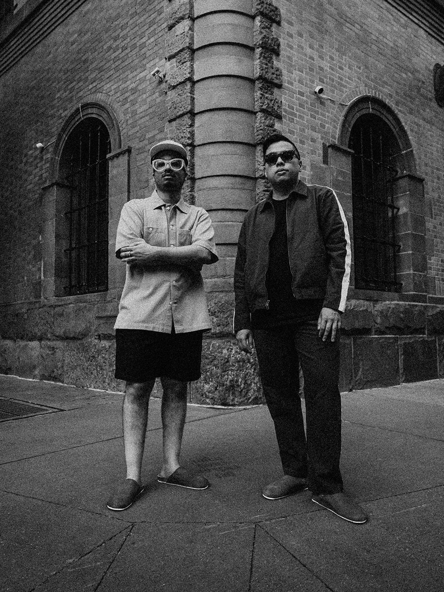 Two guys stand on a street corner in mules