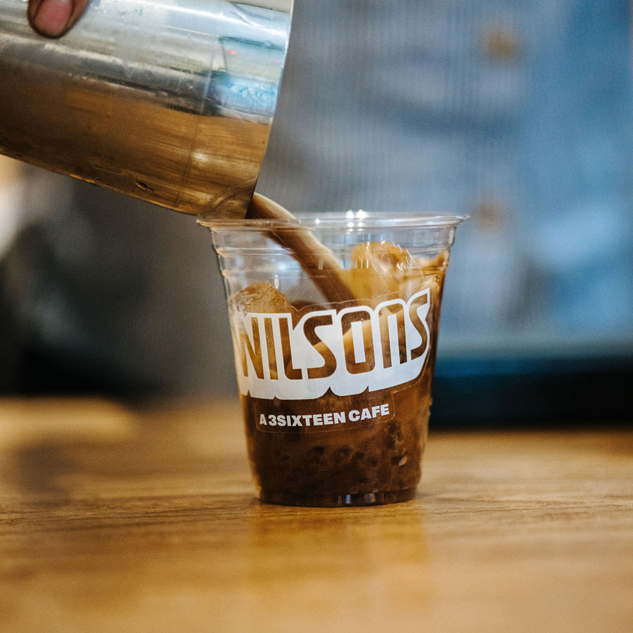 An espresso cocktail poured into a plastic cup with the Wilson's logo on it.