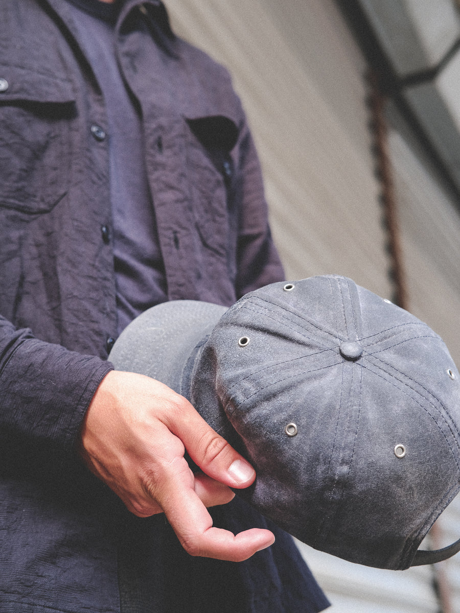 A waxed canvas baseball cap held in hand.