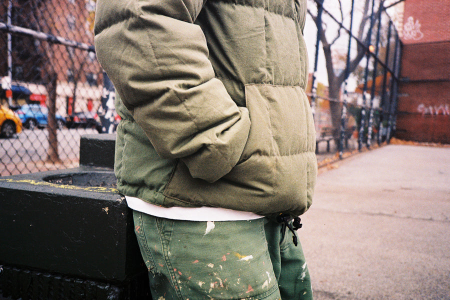 A close up shot of a paneled olive down jacket made of vintage army materials.