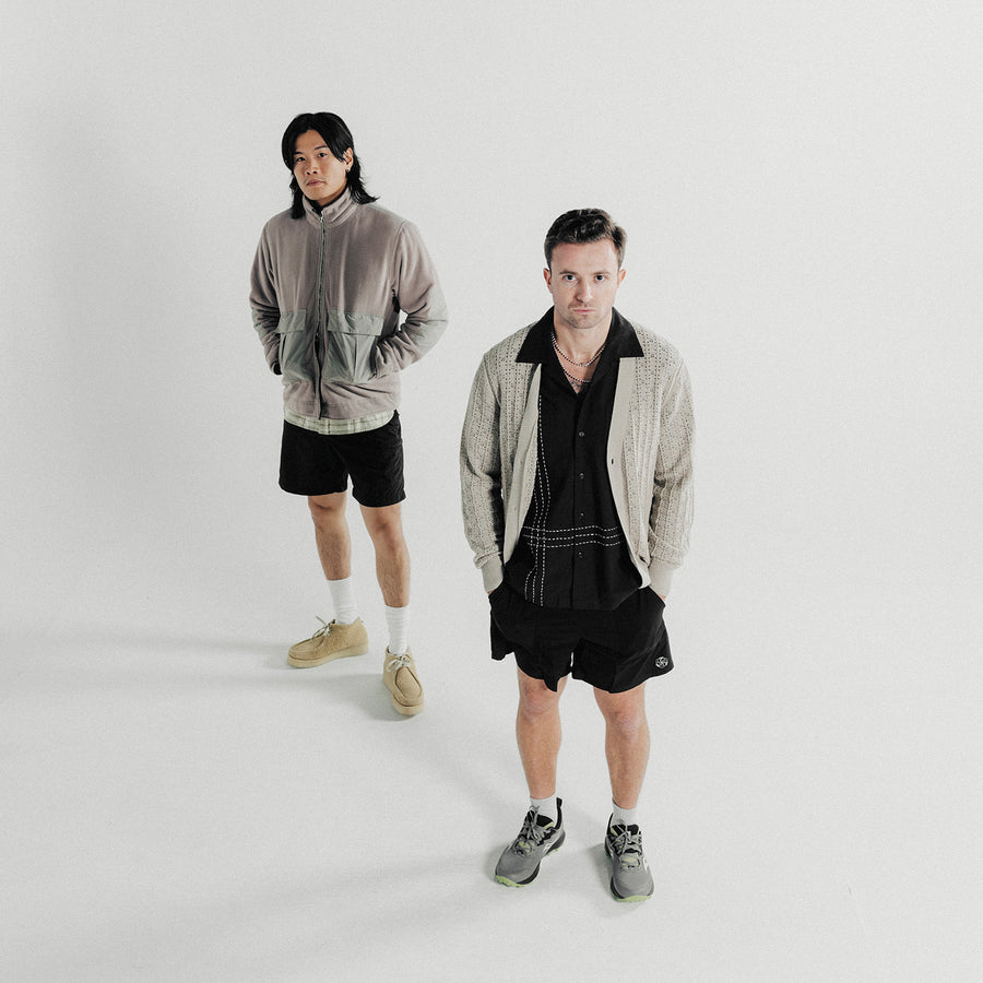 Two men pose in grey tops and black shorts.