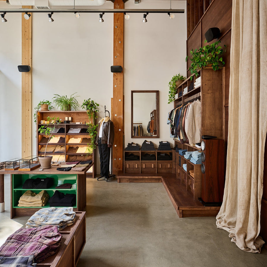 A storefront with plants on shelves and dark wood fixtures.