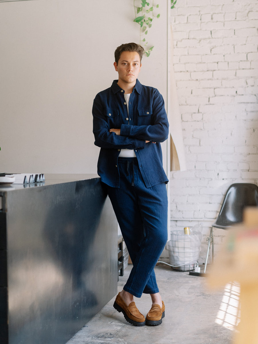 A man in a blue shirt and pants stands in a room.