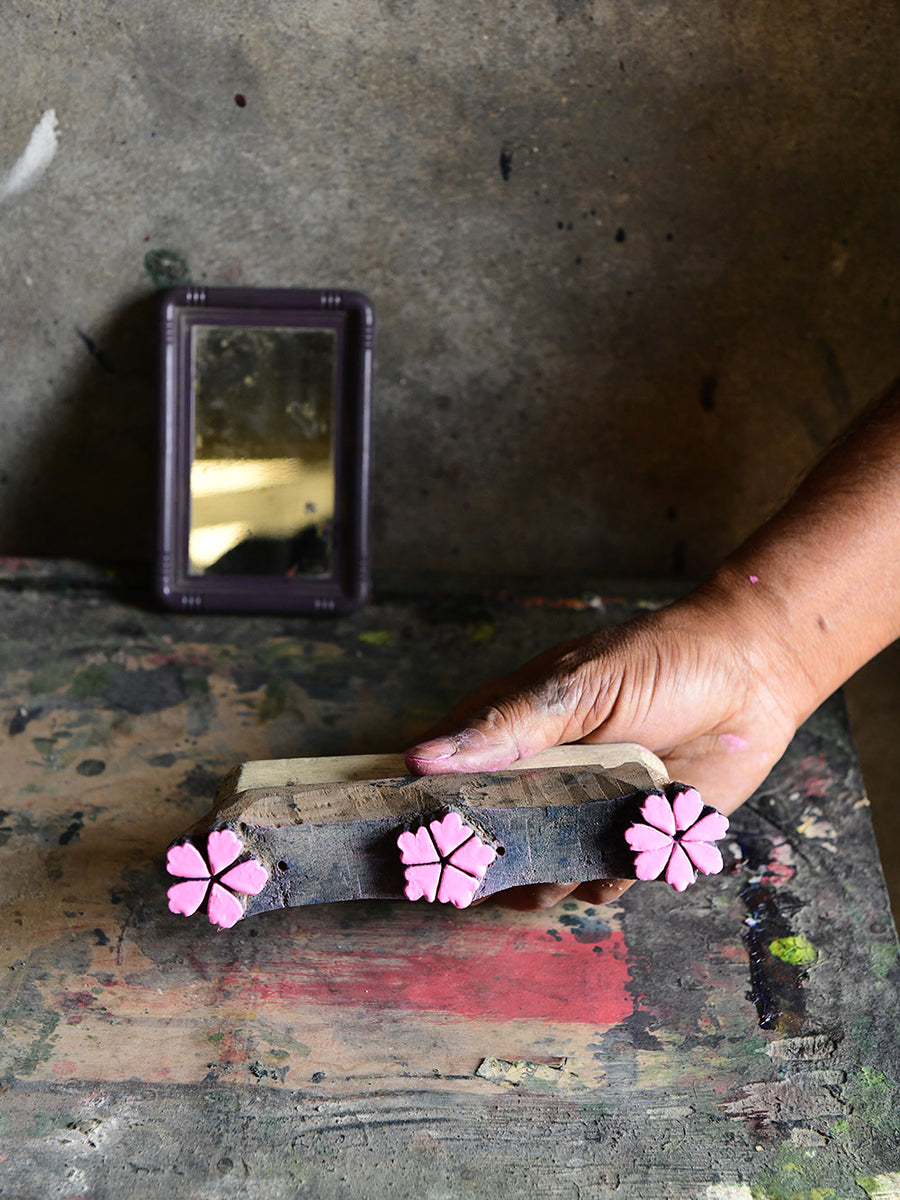 Someone holds a wooden block with sakura blossoms carved into it.