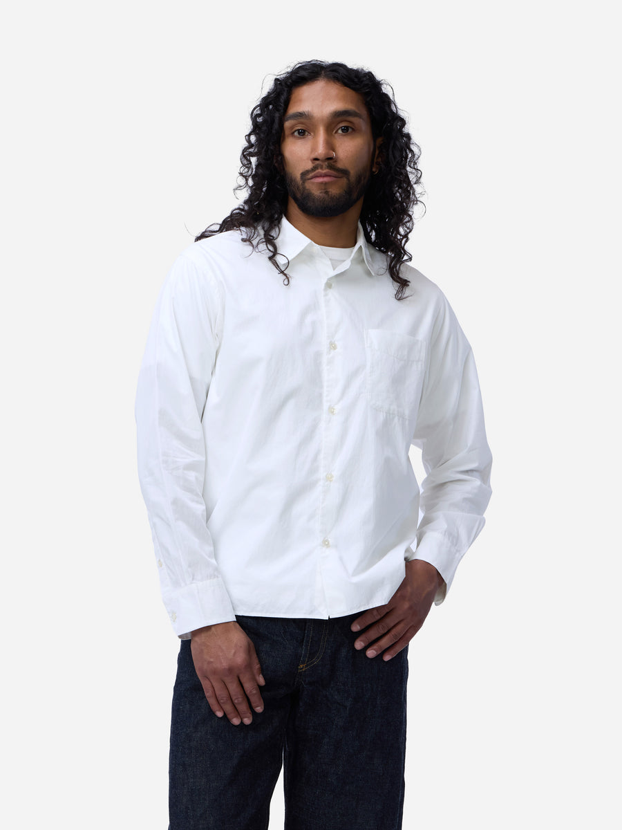 Man wearing a white button-up shirt and dark pants on a white background