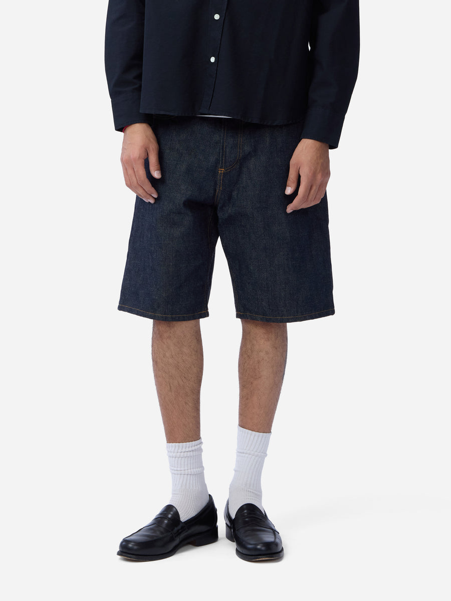 Person wearing dark denim shorts, black shoes, and white socks on a white background