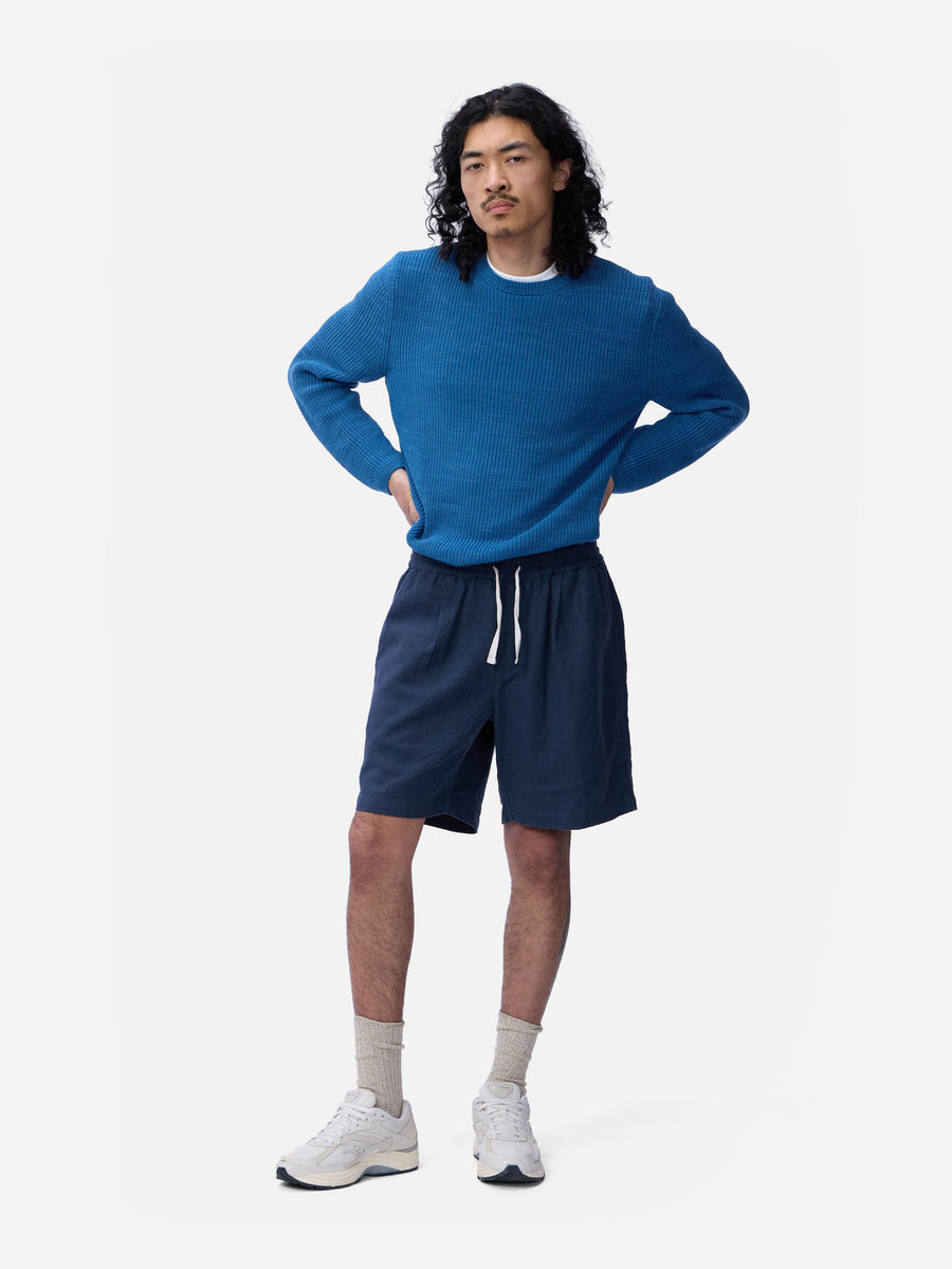 Person wearing a blue sweater and shorts on a white background