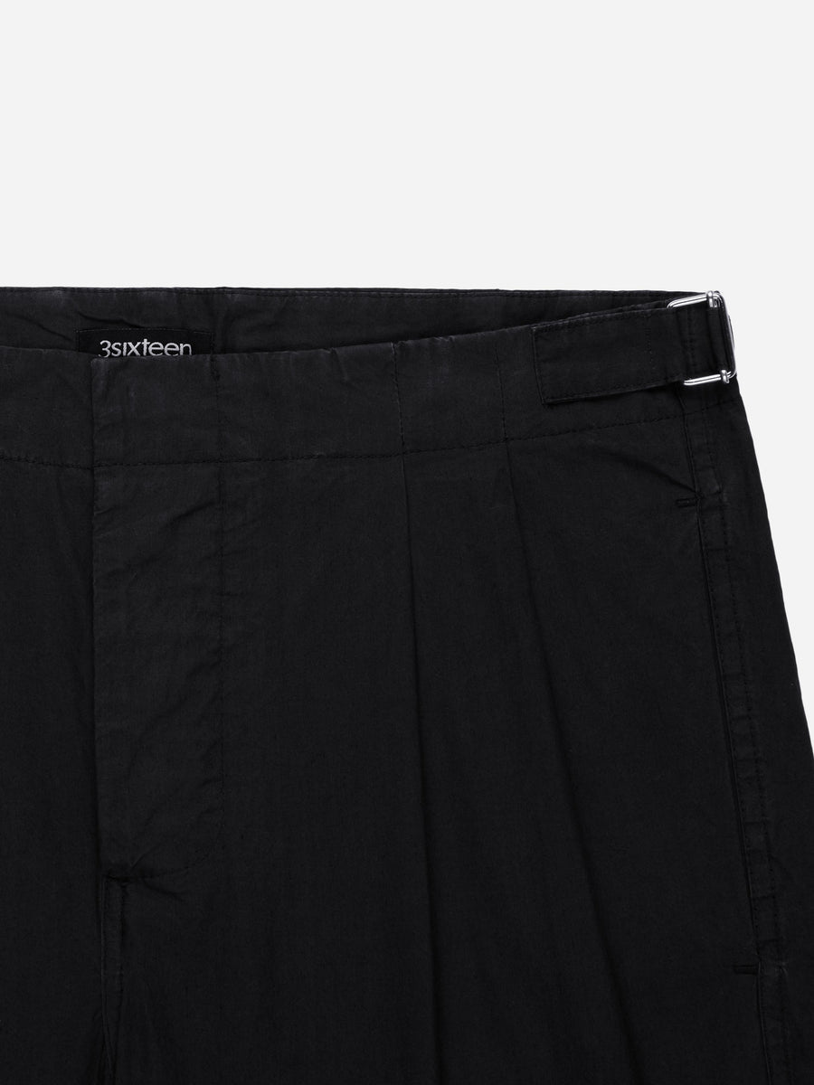 Close-up of black pants with a brand logo on a white background