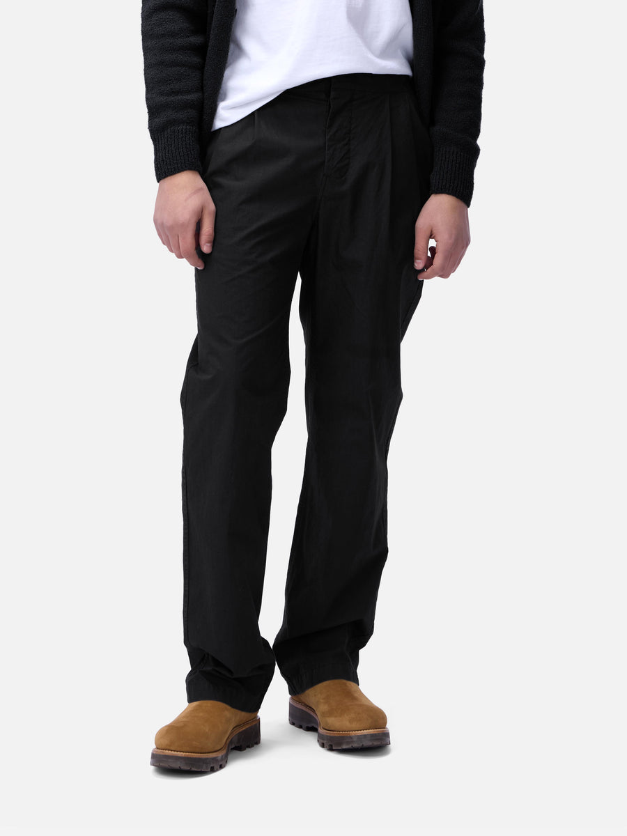 Person wearing black pants and brown shoes on a white background