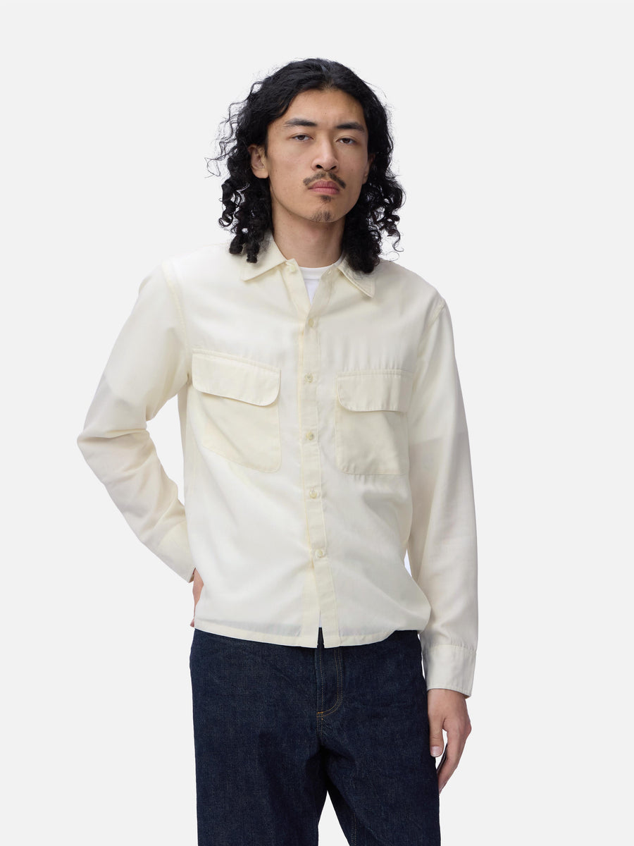Man wearing a light-colored shirt and dark pants on a white background
