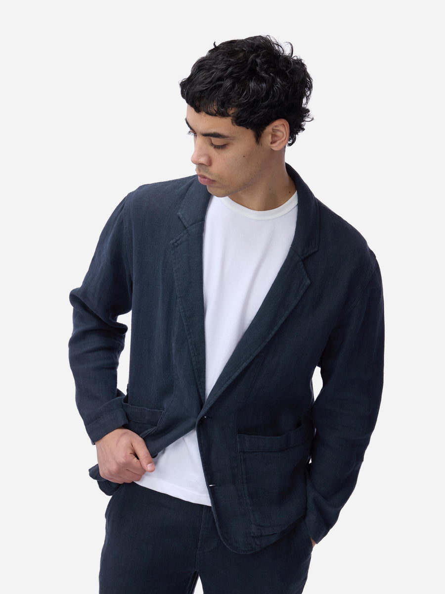 Man wearing a dark blue blazer over a white shirt on a white background