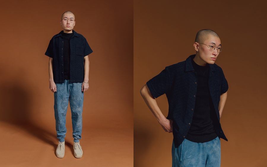 A man in a black shirt and indigo sweatpants. 