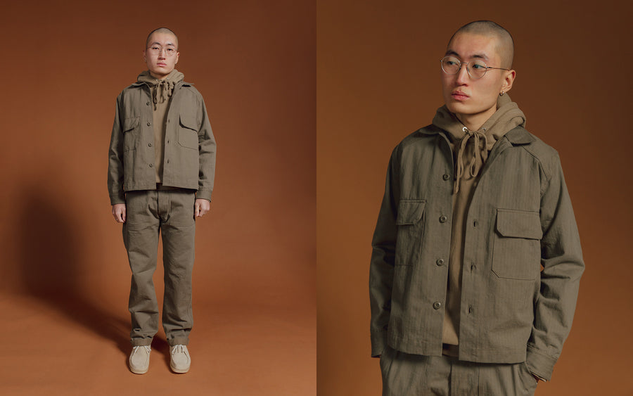 A man in a full herringbone olive suit. 