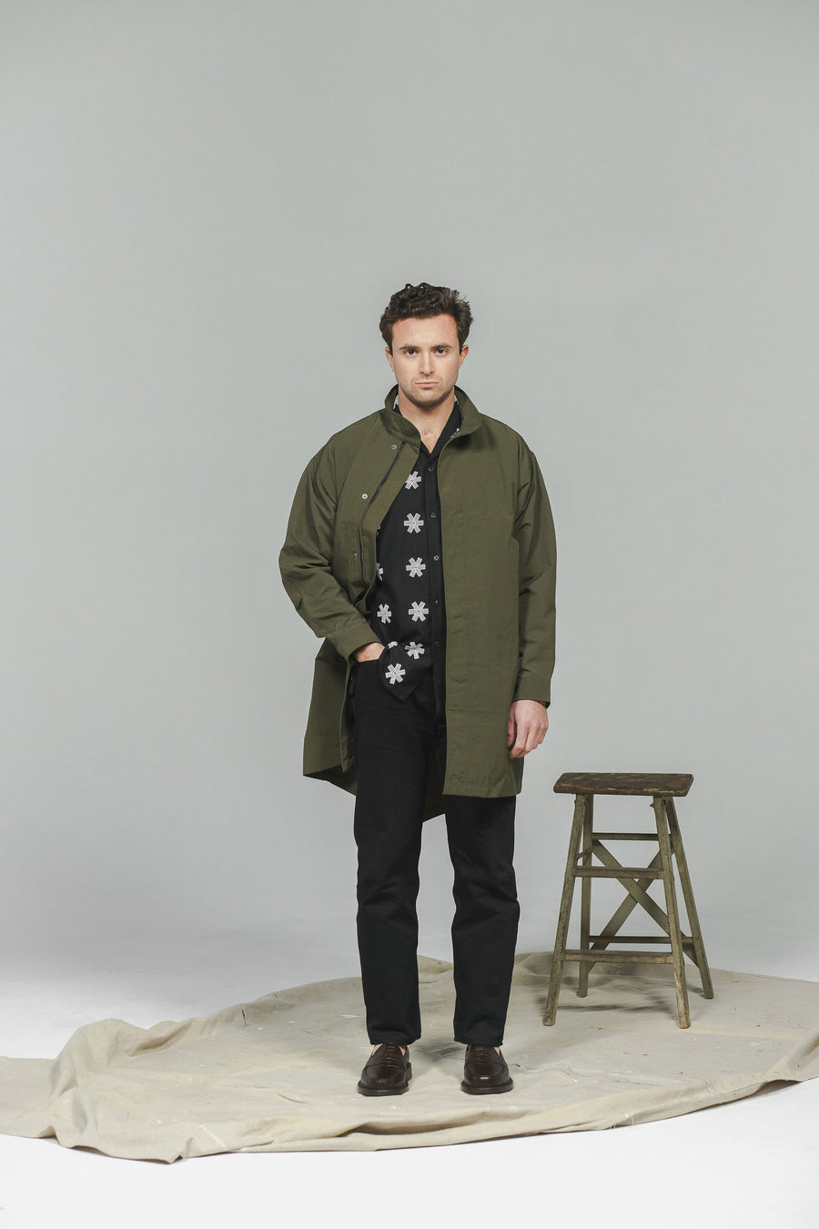 A man in an olive jacket and black jeans.
