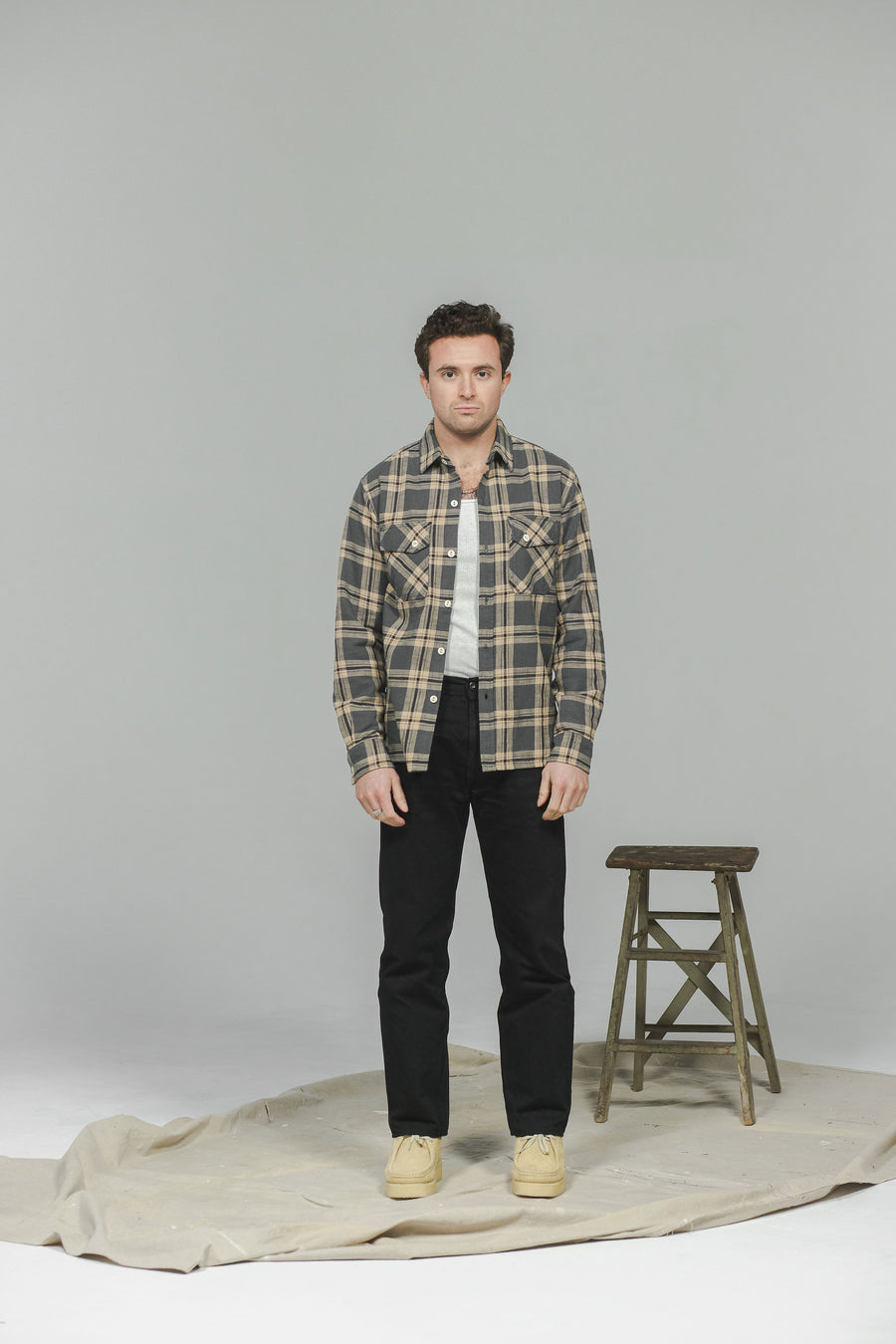 A man in a greyish blue flannel and black jeans.