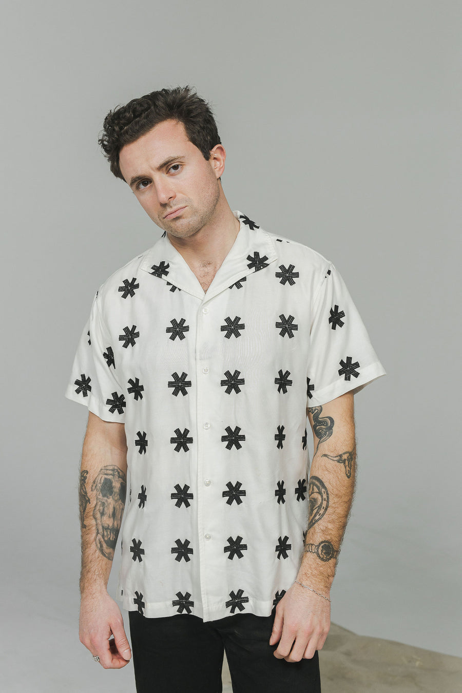 A portrait of a man in a white shirt with black star embroidery.