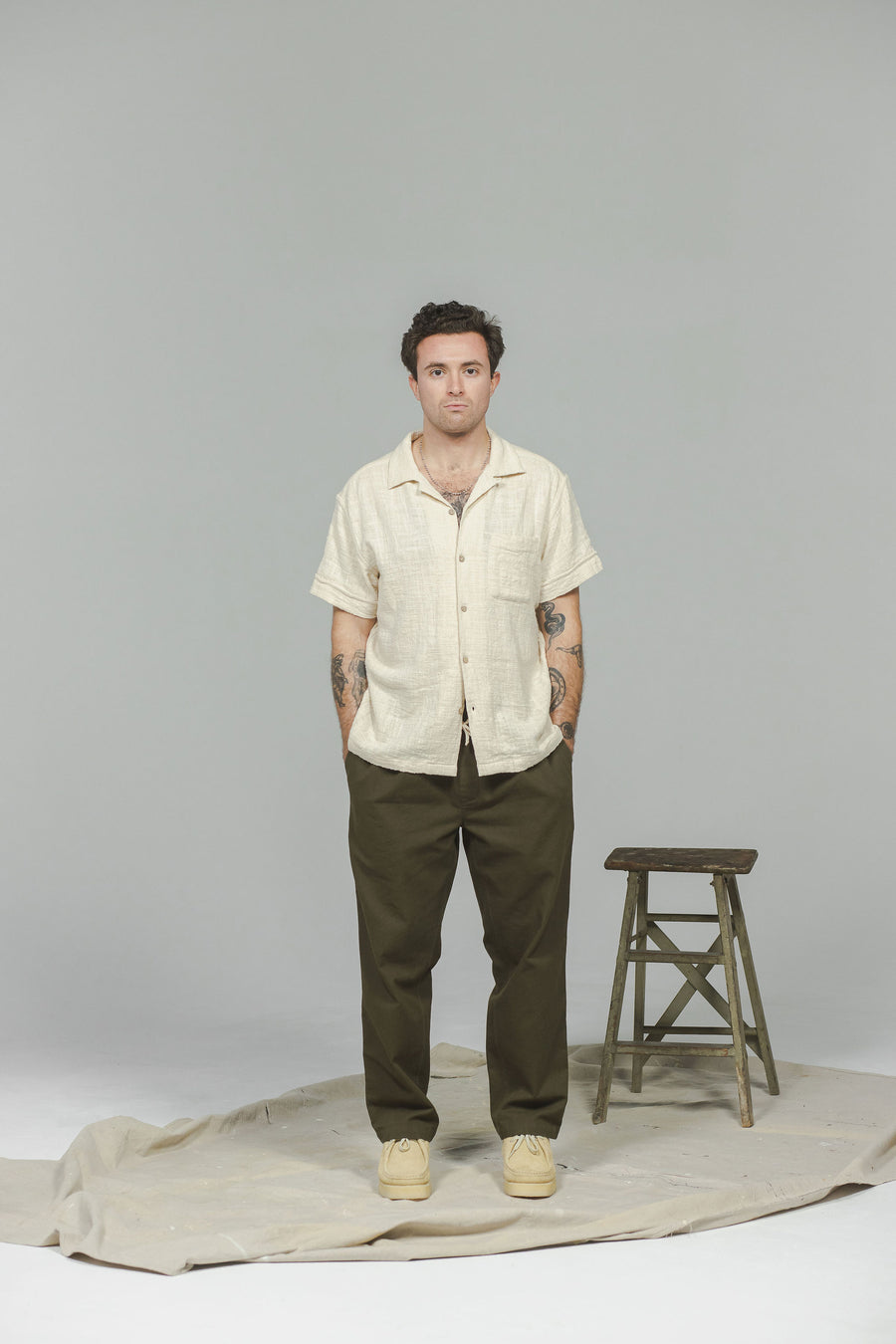 A man in a cream shirt and olive pants. 