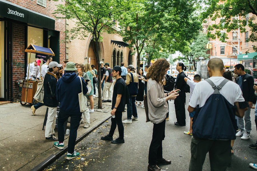 A group of people stand outside the 3sixteen store on a nice day.