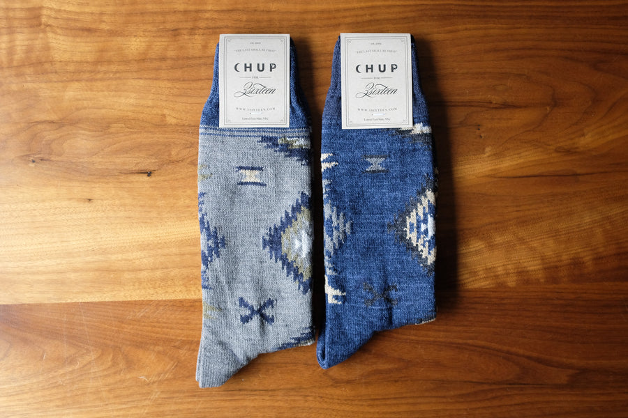 Two pairs of socks lying flat on a wooden surface.