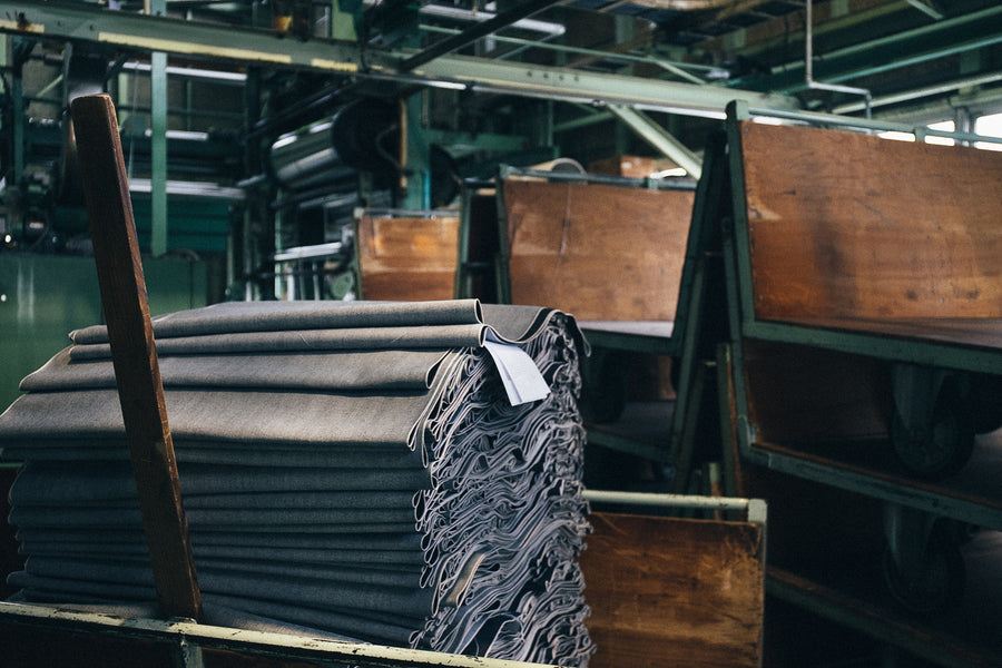A neatly folded pile of raw denim fresh off the loom sits in an old wooden cart.