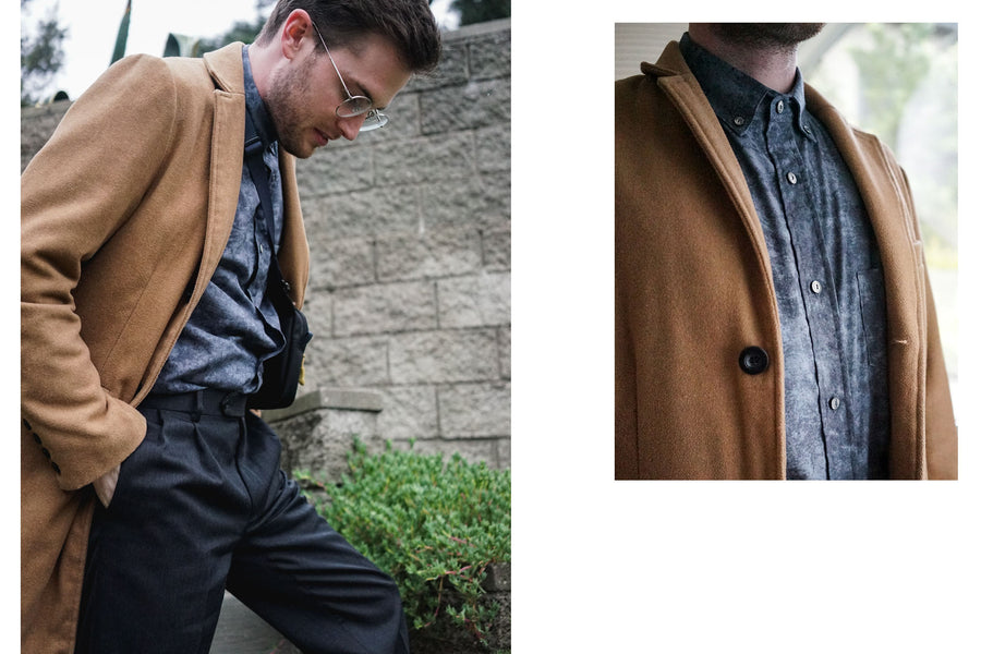 A man in a camel overcoat with a 3sixteen BD Shirt in Charcoal Haze steps out into the garden.