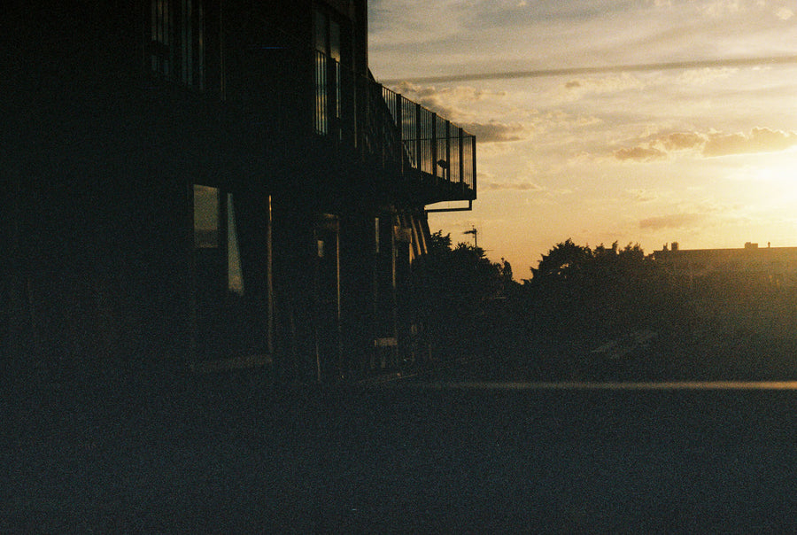 The sun sets over an outdoor porch.