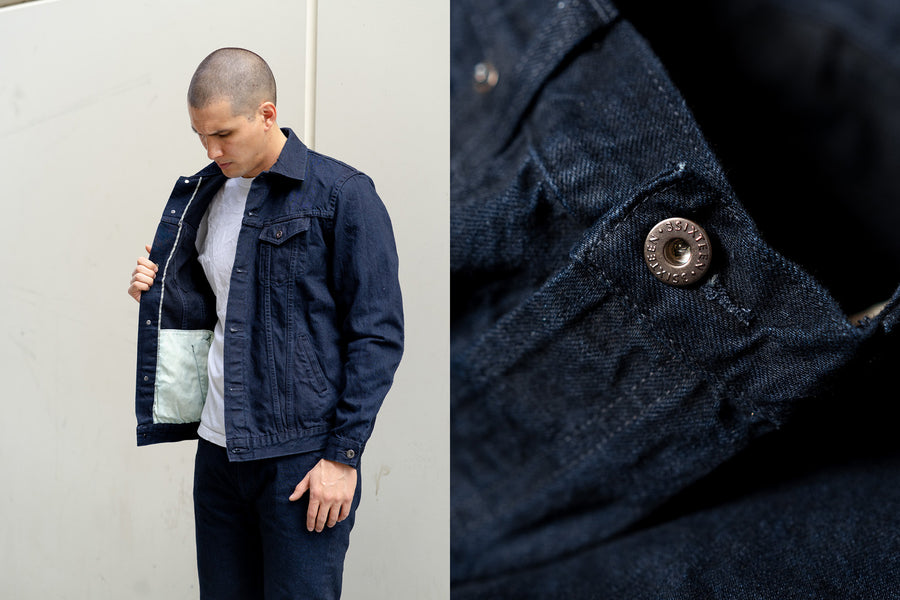 A man looks at the inside of his dark blue denim jacket.