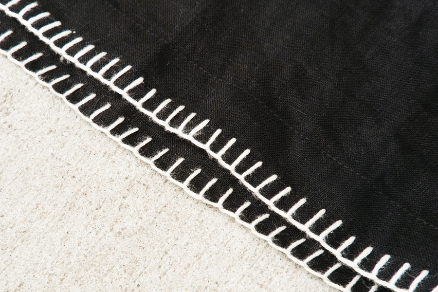 An up close detail shot of the hand stitching detail on the linen shirt.