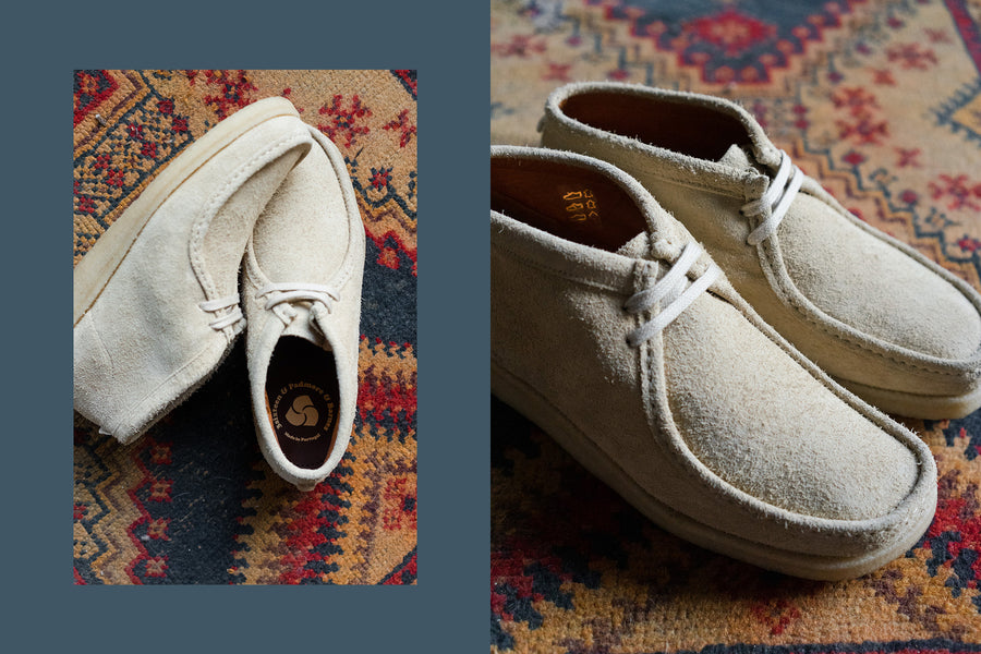 A pair of light sand hairy suede shoes on a colorful rug.