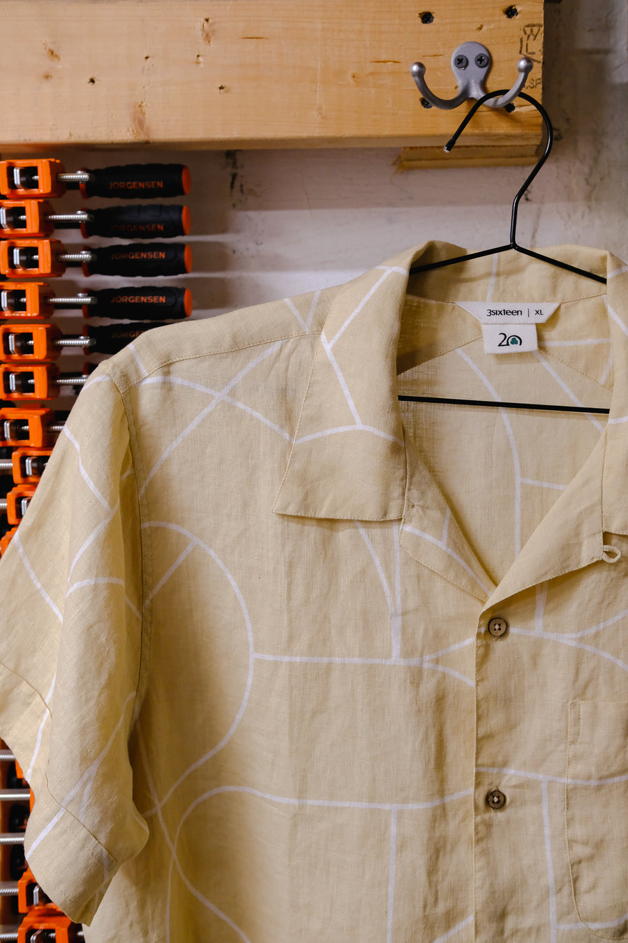 A tan shirt on a black hanger.