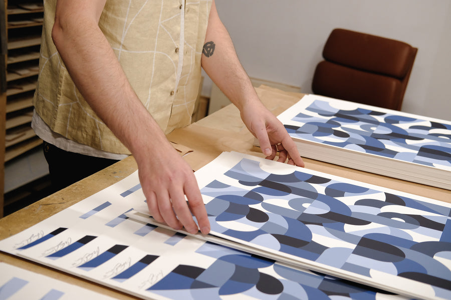 A man rearranges prints on a table.