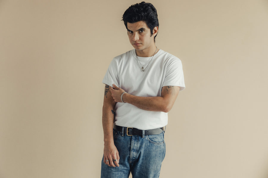 A close up shot of a handsome man in a white tshirt and blue jeans.