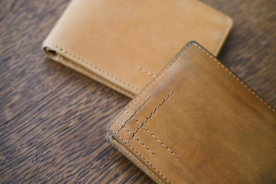 A brand new tan wallet next to an old, worn-in one.