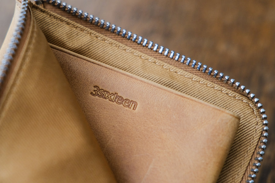 The interior of a wallet shows a logo stamp and a textile lining.